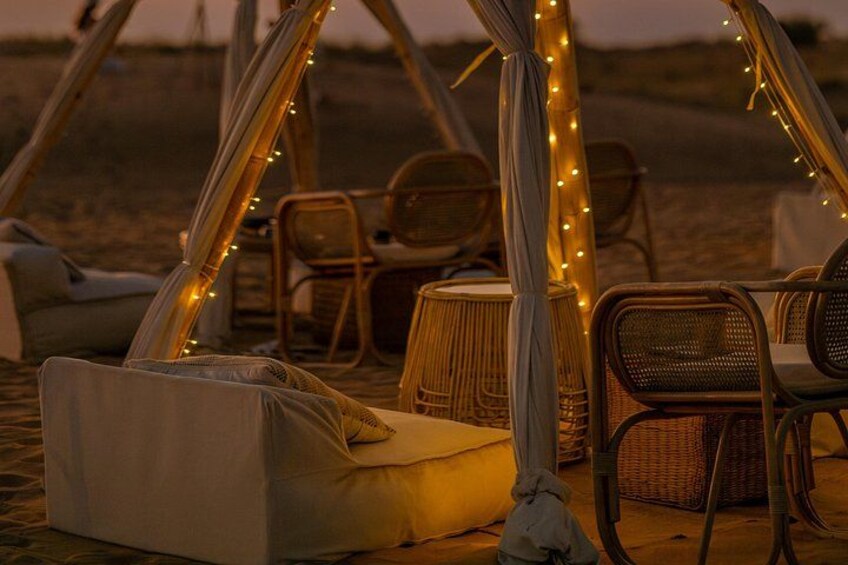 A tent with chairs and a drum, decorated with string lights. 4