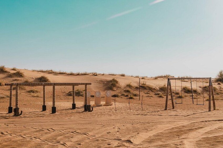 A desert landscape with sand dunes and a structure with a target in the background. 5