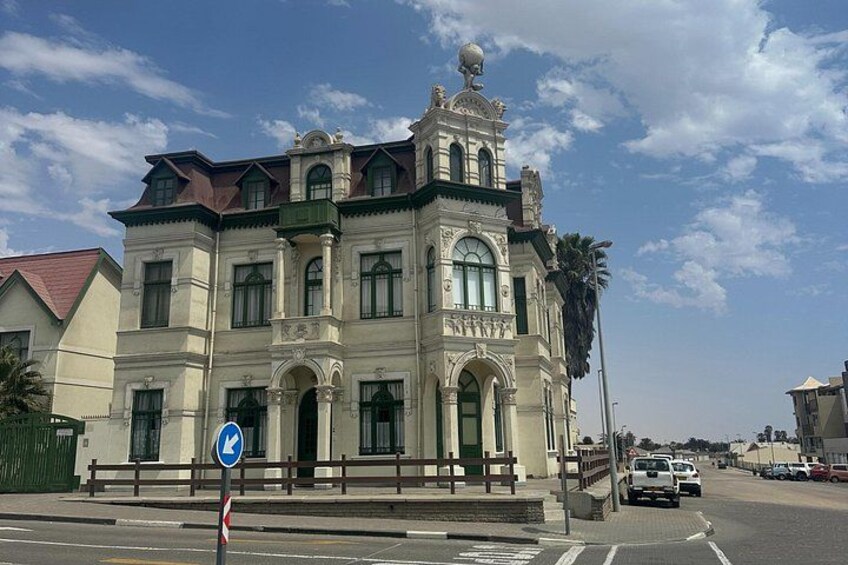 Ein historisches Gebäude mit aufwendiger Architektur, einem Straßenschild und einer Palme. 1