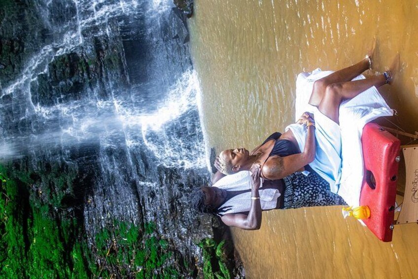 A person lying on a beach with a suitcase and a red bag, overlooking a waterfall. 3