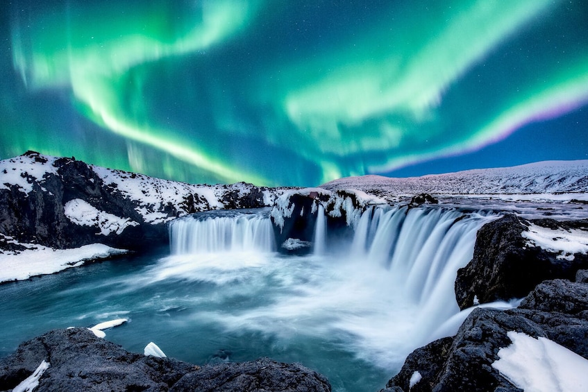 Una cascata con rocce imbiancate dalla neve e vista sull'aurora boreale. 1