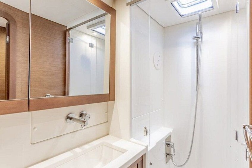 Een badkamer met een wit wastafelmeubel, een spiegel en een douche. 3