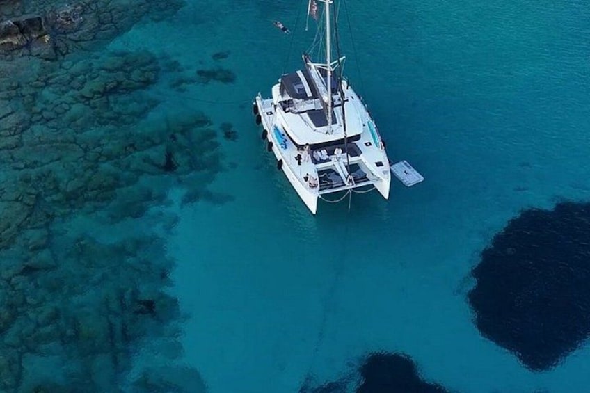 Un velero blanco anclado en aguas turquesas cristalinas con formaciones rocosas cerca. 2