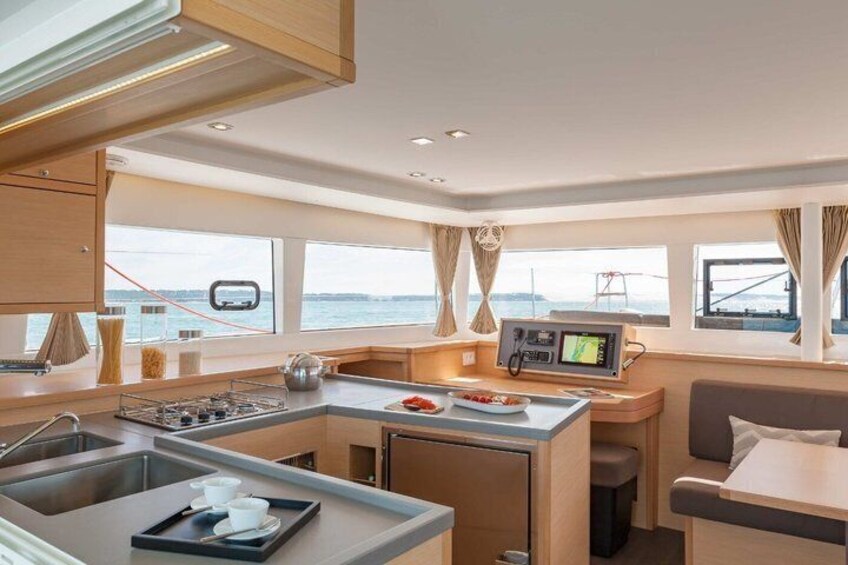 A compact galley with a stove, sink, and a small seating area with a table and chairs. 2