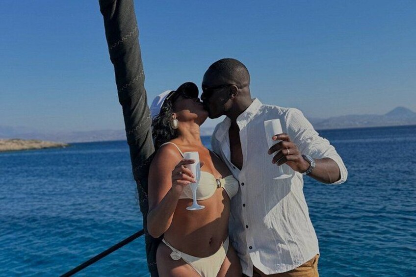 A couple on a boat with a clear blue sea and distant mountains in the background. 2