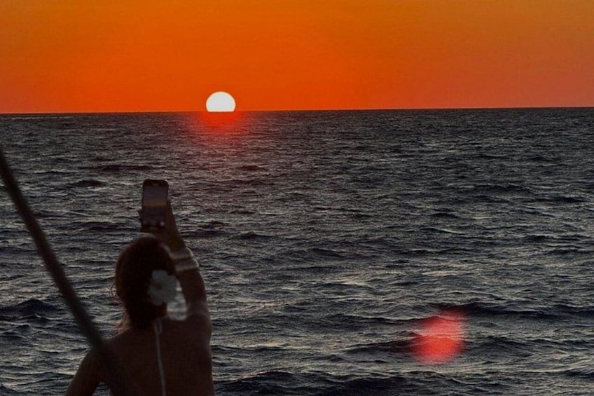 Un atardecer sobre el océano con una persona fotografiando. 3