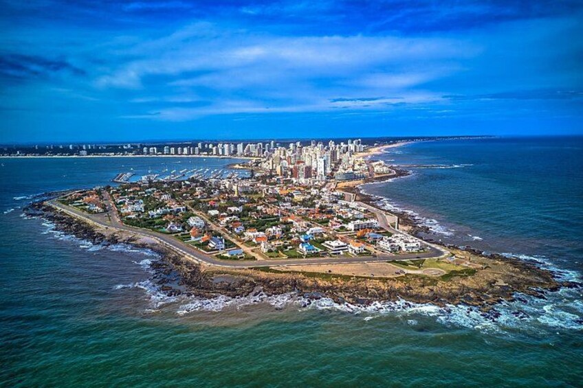 Un paisaje urbano costero con una prominente península, edificios urbanos densos y una vista despejada del océano. 1