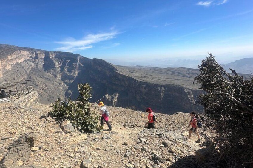 A rocky terrain with hikers and a view of a canyon. 3