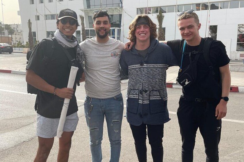 Four people standing on a street with a building in the background. 2
