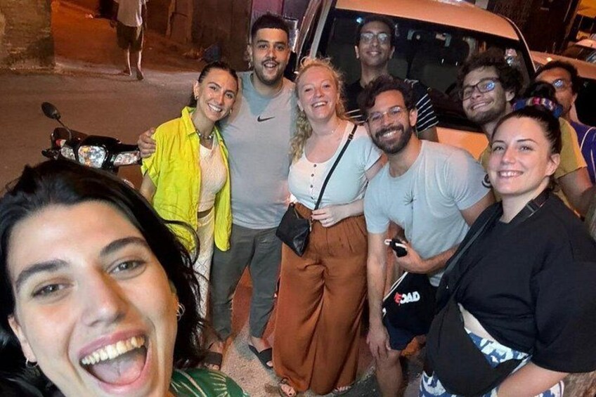 A group of people posing for a photo on a street at night. 5