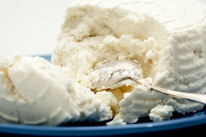 Un trozo de queso blanco sobre un plato azul con una cuchara. 3
