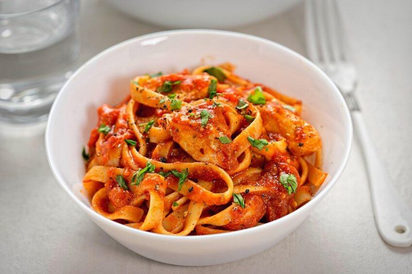 A bowl of pasta with tomato sauce and herbs. 4