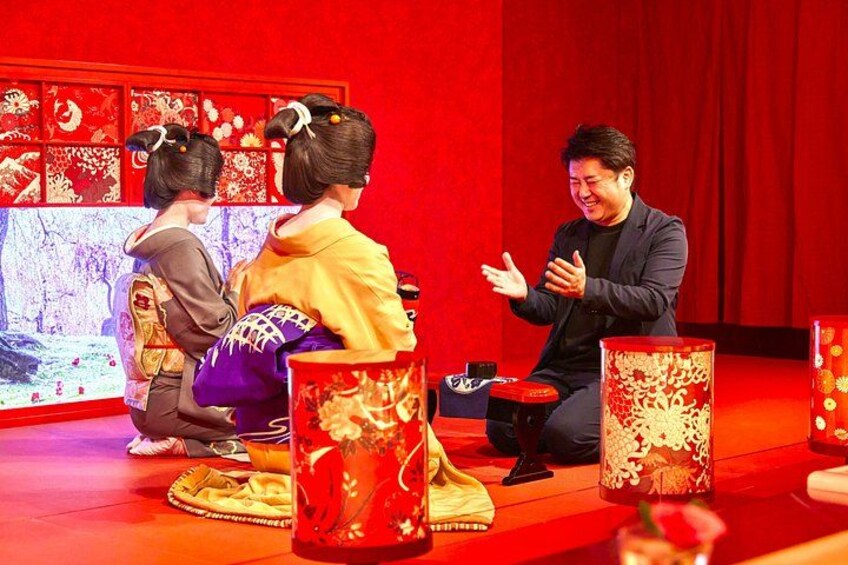 A stage with a red backdrop, a person gesturing, and traditional Japanese attire. 3