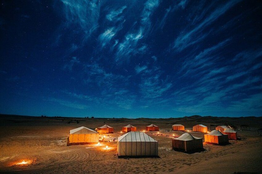 A desert landscape at night with yurts illuminated by artificial lights. 1