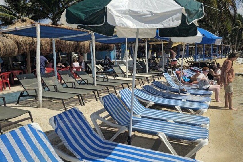 Beach chairs, umbrellas, and people on a sandy beach. 2