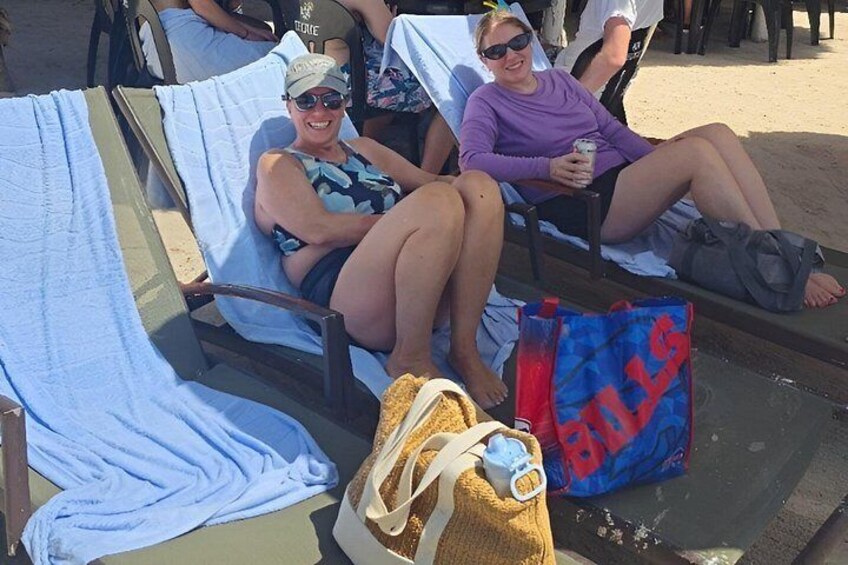 Two people relaxing on lounge chairs at a beach. 5