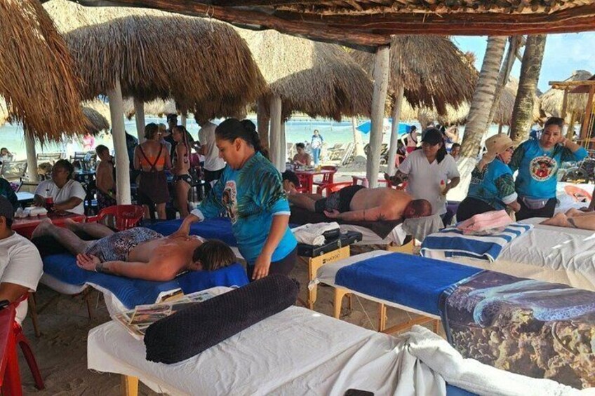 A beachside massage parlor with multiple massage tables and clients receiving treatments. 4