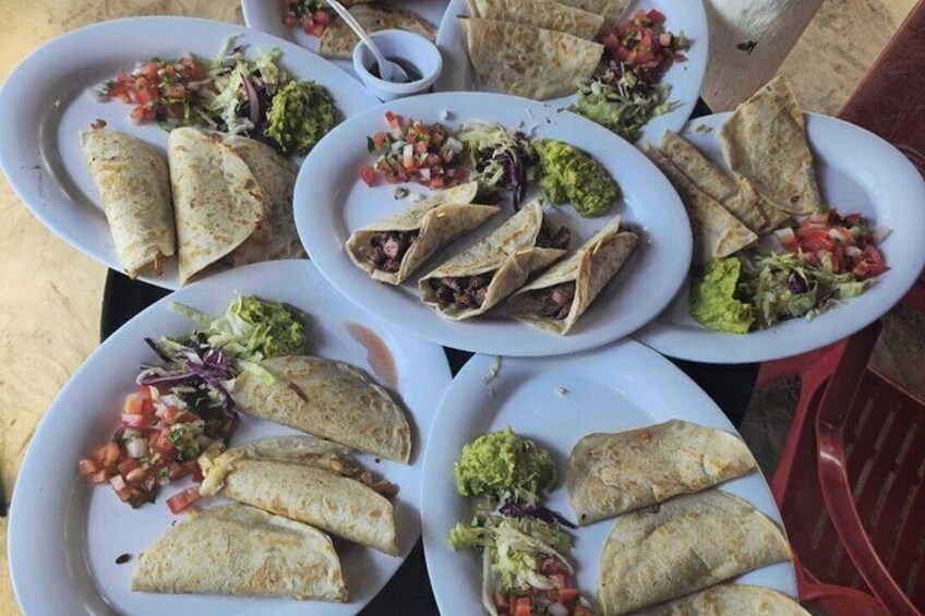 A table with plates of food, including tacos and salads. 3
