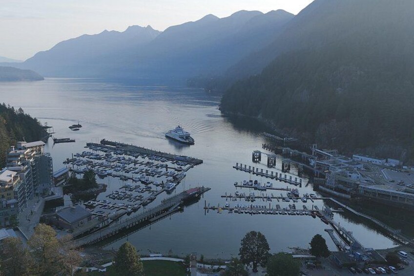 A harbor with boats, a large ship, and mountains in the background. 2