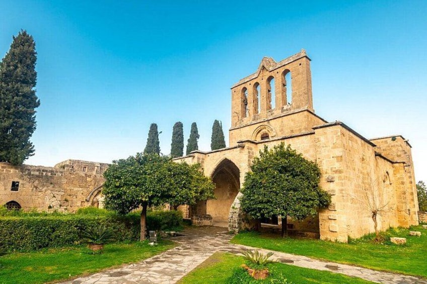 A historic stone building with a bell tower, surrounded by well-maintained greenery and a stone pathway. 4