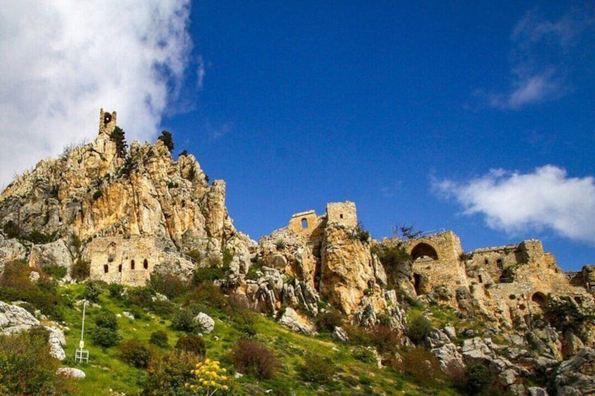 A rocky hill with ancient ruins and a clear blue sky. 2