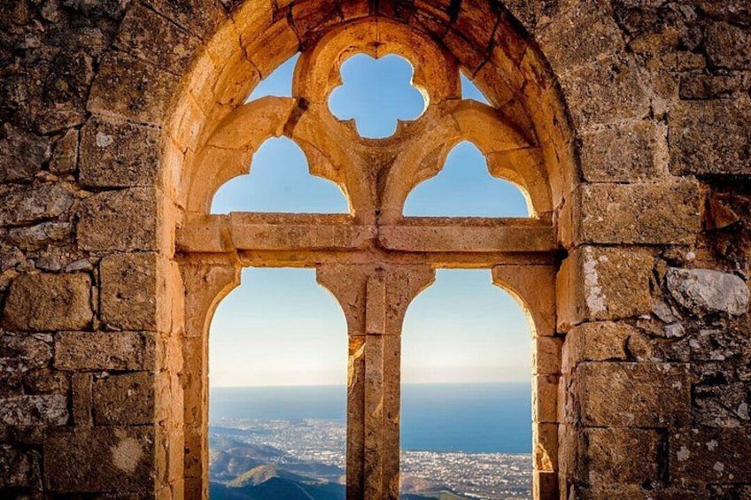 A stone archway with a view of a distant city and coastline. 3