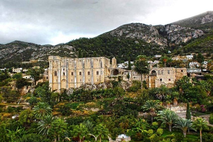 An ancient stone building surrounded by lush greenery and mountains in the background. 5