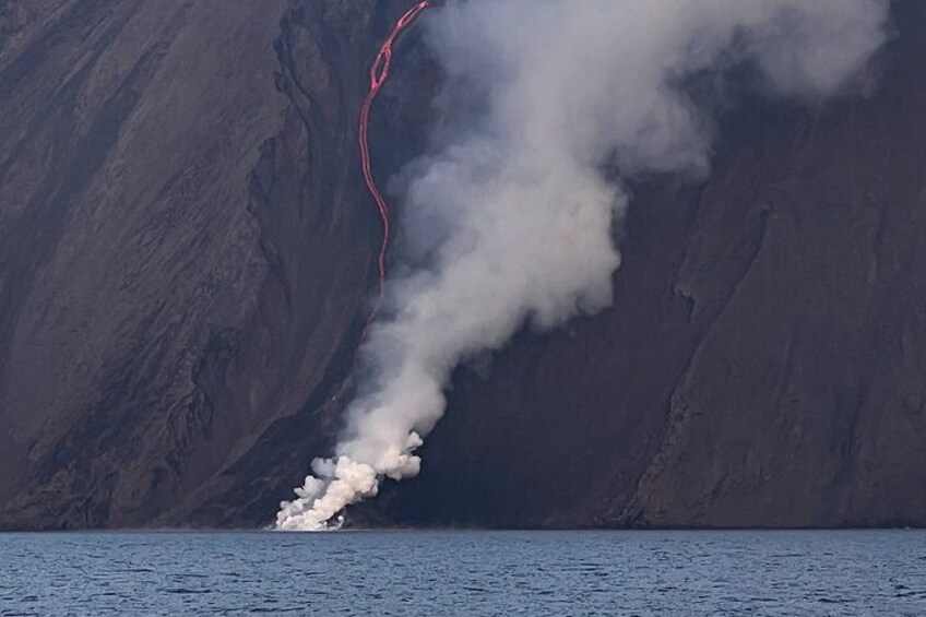 Et udbrud af en vulkan med lava, der flyder ud i havet. 1