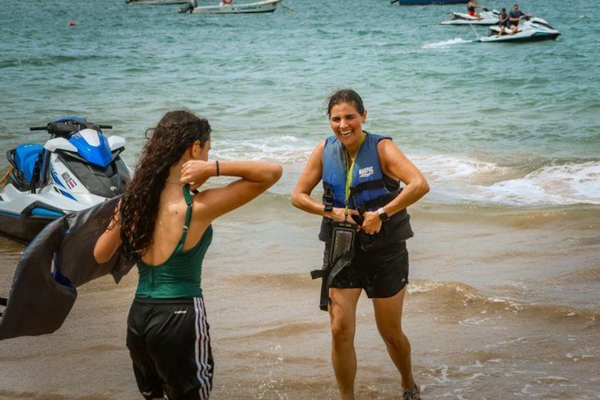 Two people on a beach with a jet ski and a boat in the background. 5