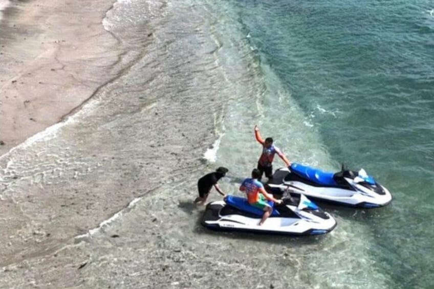 A beach with two jet skis and a dog near the water's edge. 3