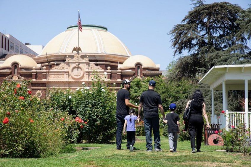Un grupo de personas caminando en un jardín con un edificio grande al fondo. 2