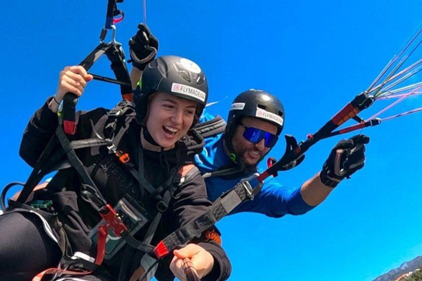 Two people paragliding with harnesses and parachutes. 1