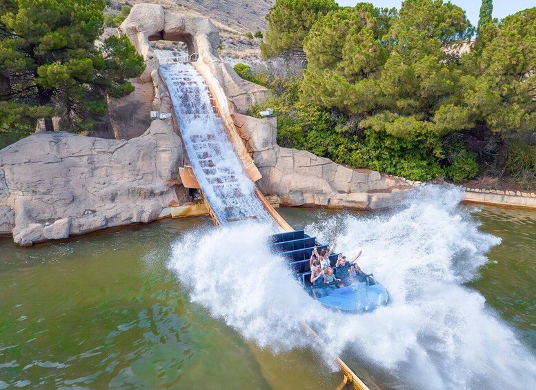 A water slide with a boat at the bottom, surrounded by rocky terrain and trees. 5