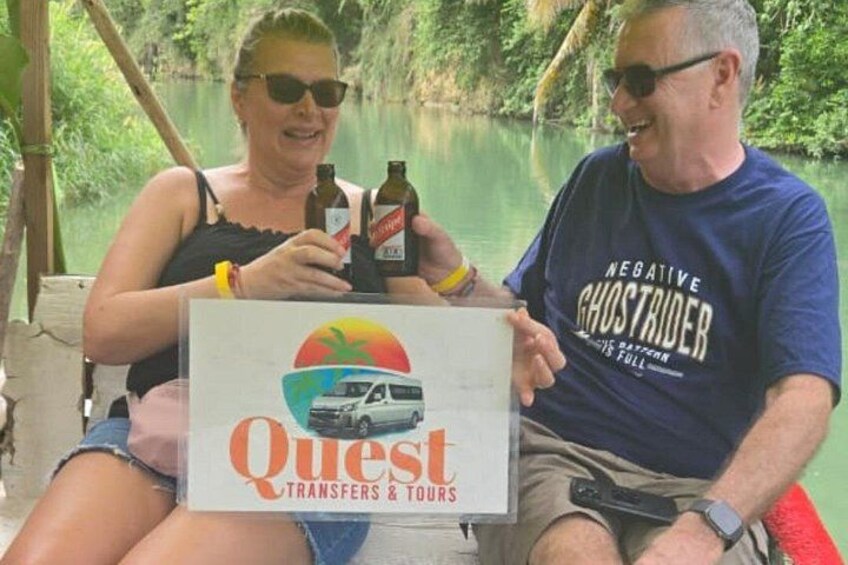 Deux personnes tenant une pancarte sur laquelle on peut voir un véhicule et les mots « Quest Transfers & Tours ». 5