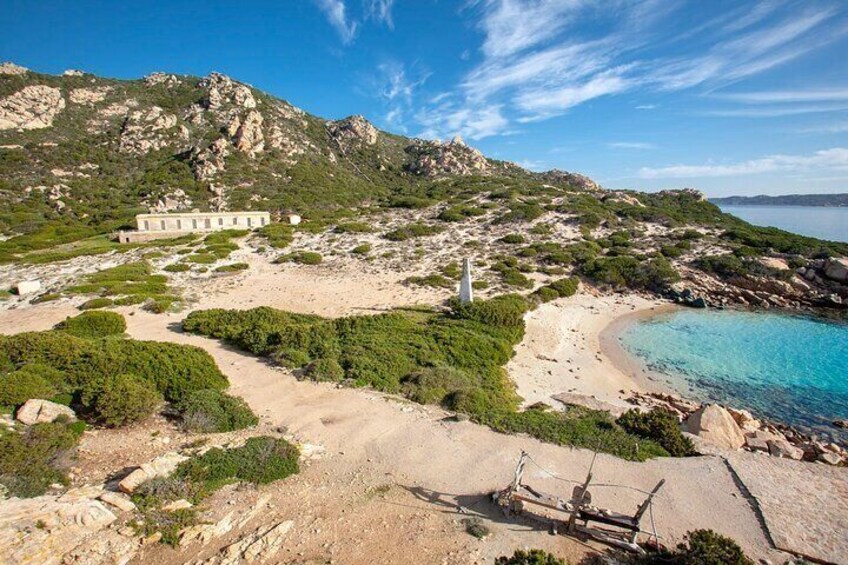 A coastal landscape with a beach, rocky terrain, and a building. 5