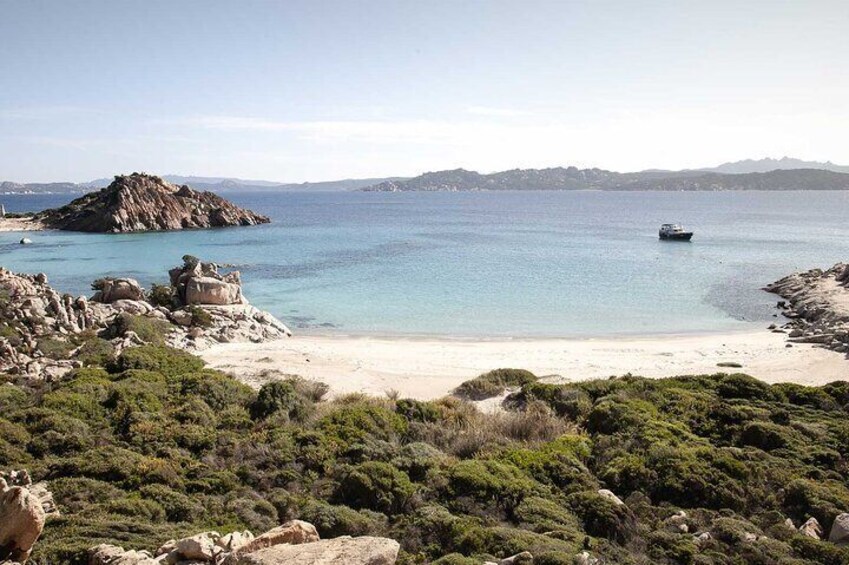 A coastal landscape with a sandy beach, rocky outcrops, and a boat on the water. 2