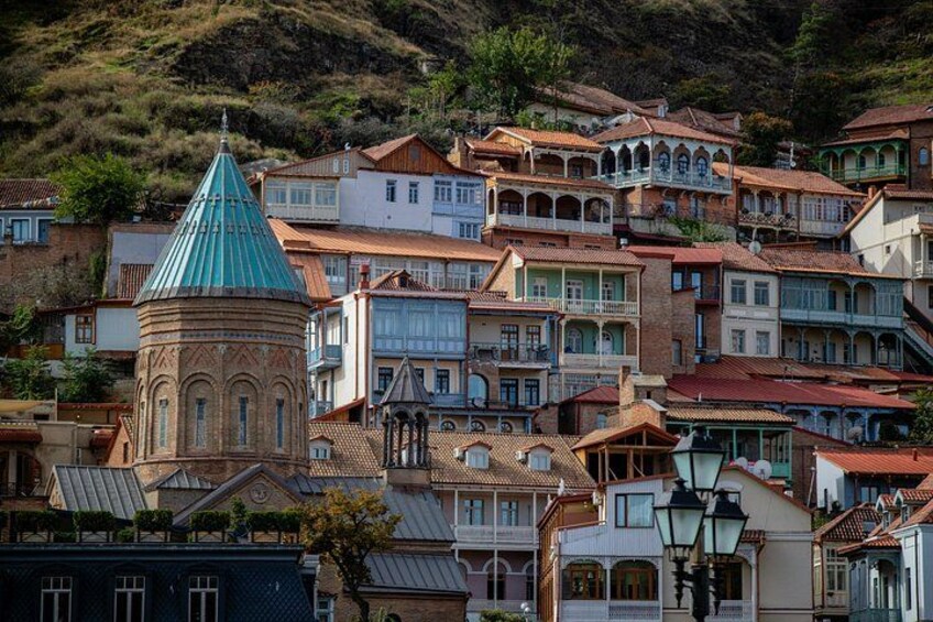 Un pueblo en la ladera de una colina con edificios escalonados, una iglesia destacada con cúpula verde y arquitectura tradicional. 2