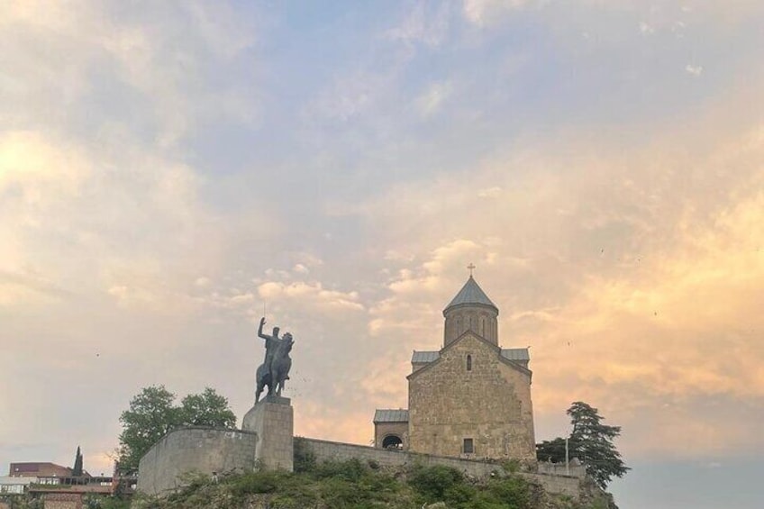 A statue on a pedestal, a church, and a tower. 4