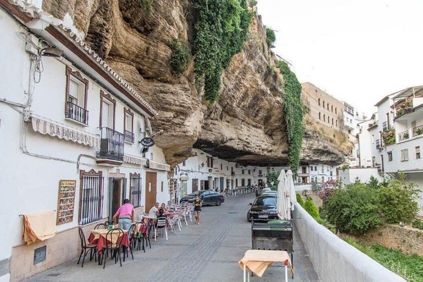 Una calle con edificios, un acantilado y coches aparcados. 3