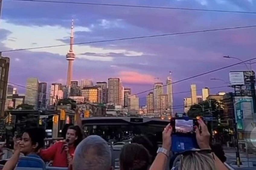 Un paisaje urbano con una torre destacada, un tranvía y personas tomando fotografías. 3