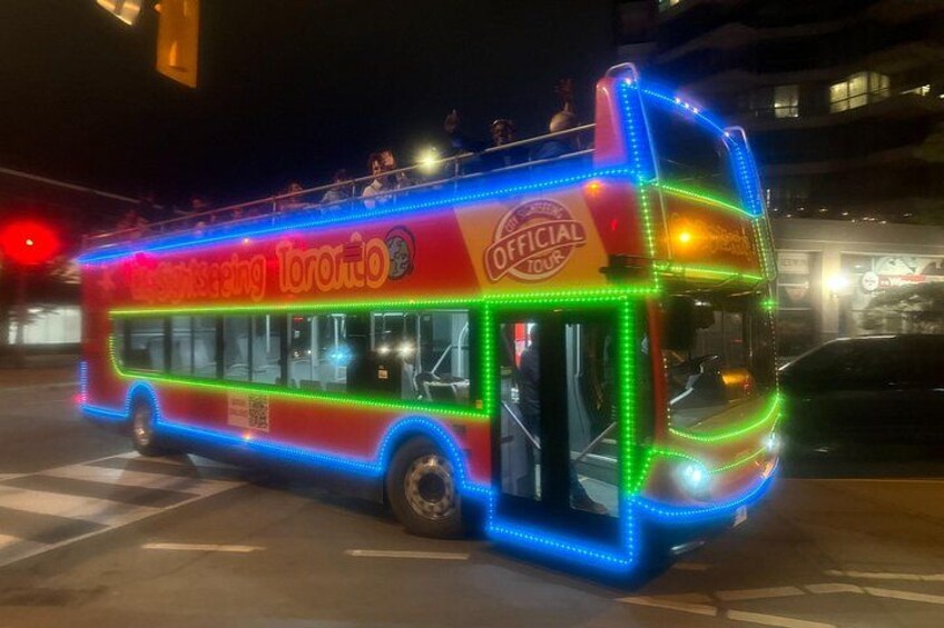 Un autobús de dos pisos con luces LED de colores y el texto 'Toronto Sightseeing Tour' en la lateral. 2