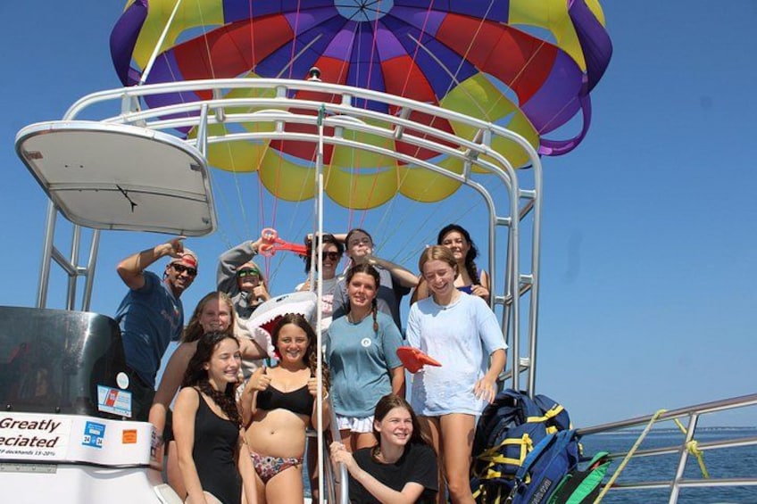 A group of people on a boat with a colorful parachute above them. 2