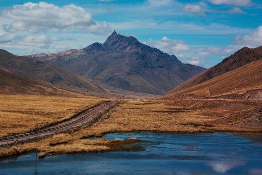 Un río con una vía de tren que lo acompaña, rodeado de montañas. 5