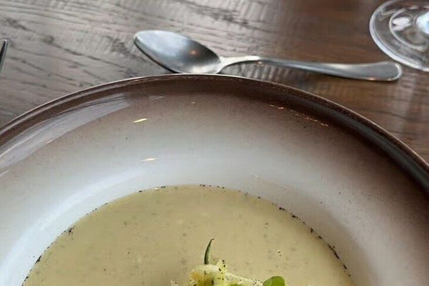 A bowl of soup with a spoon and a glass on a wooden table. 5