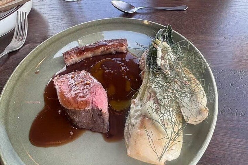 A plate of food with a steak, a fish fillet, and a vegetable. 4