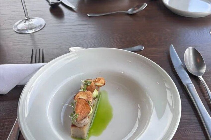 A white plate with a green sauce, a piece of food, and a fork. 3
