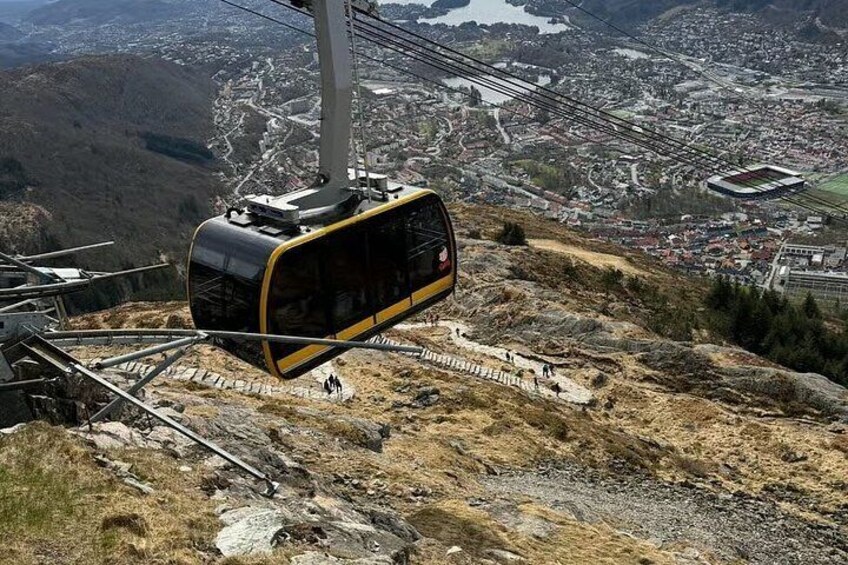 A cable car suspended over a mountainous landscape with a town below. 2