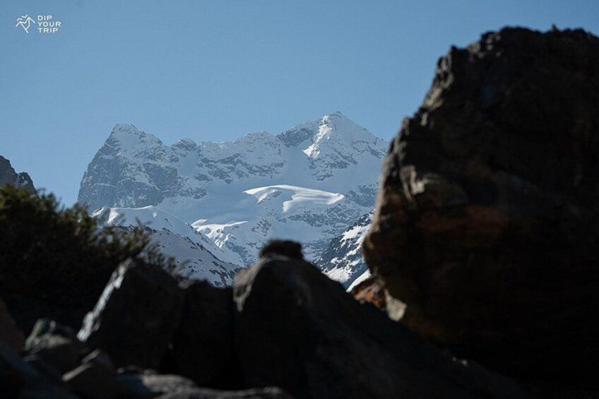 A mountain range with snow-covered peaks and rocky foreground. 2