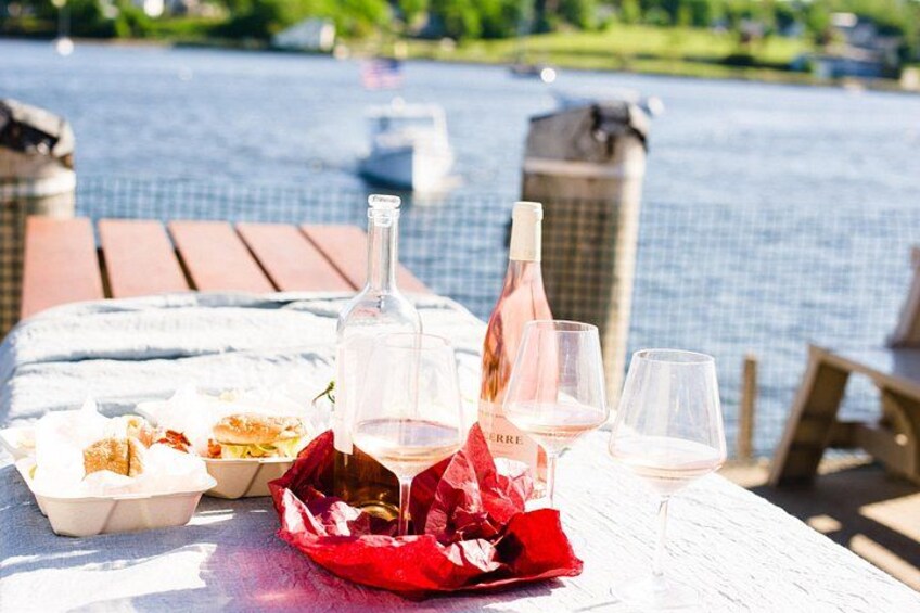 A picnic table with food, wine bottles, and glasses by a pool. 3