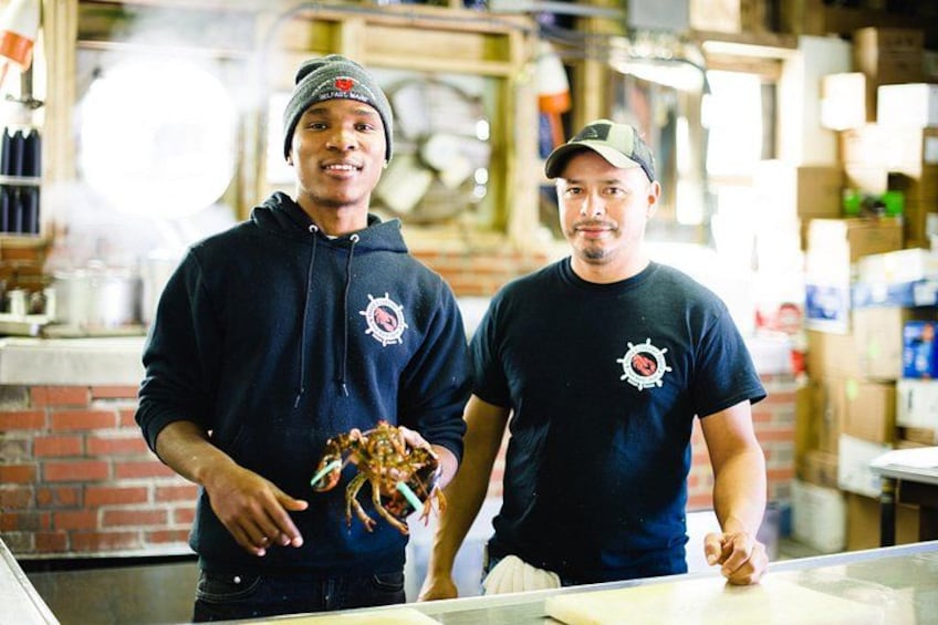 Two individuals in a kitchen holding a crab. 2